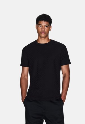 Camiseta de algodón negra con un patrón texturizado, mangas cortas y un escote redondo, con un ajuste regular y dobladillo recto.