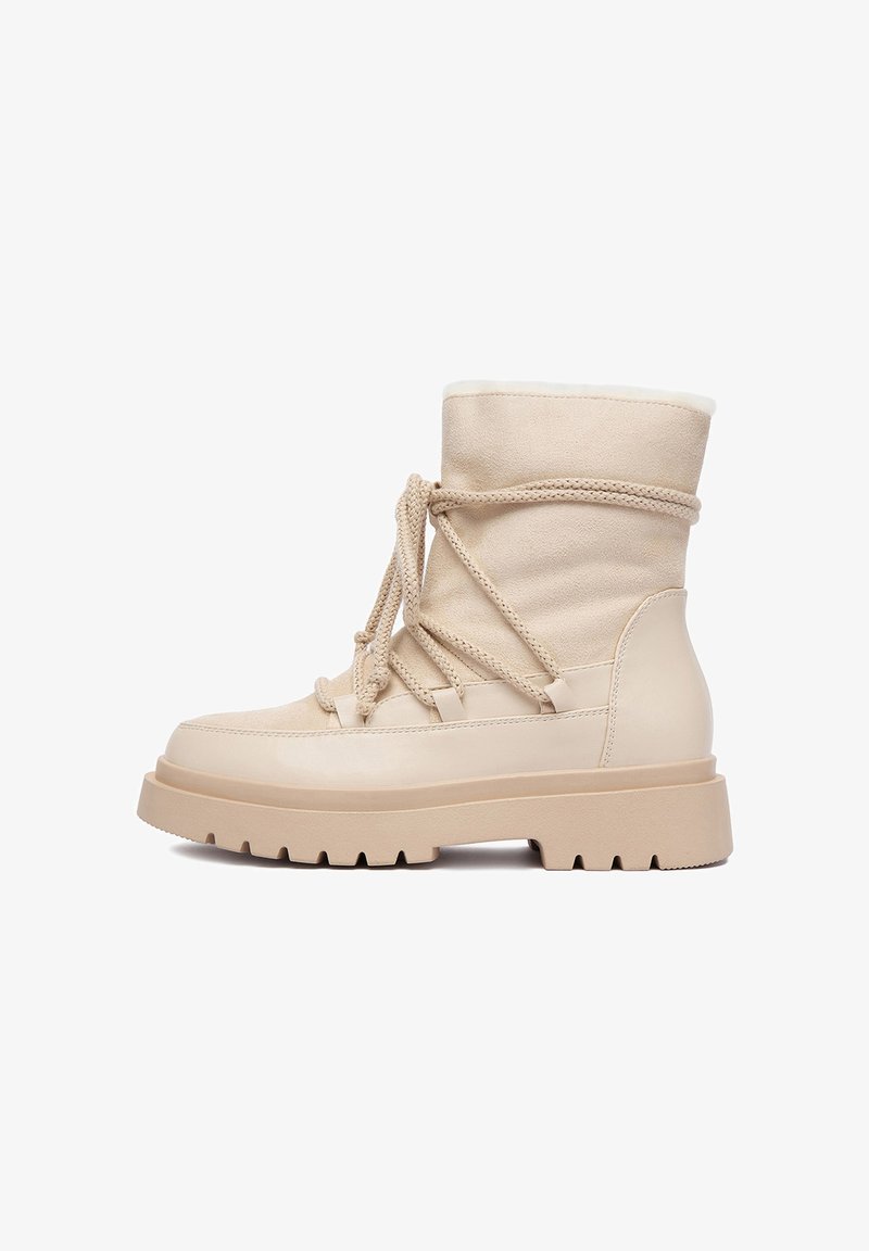 Botine bej cu sireturi, realizate dintr-un amestec de piele și daim, cu detalii din panouri texturate și o talpă din cauciuc rezistentă. Căptușeală din blană moale la partea de sus.