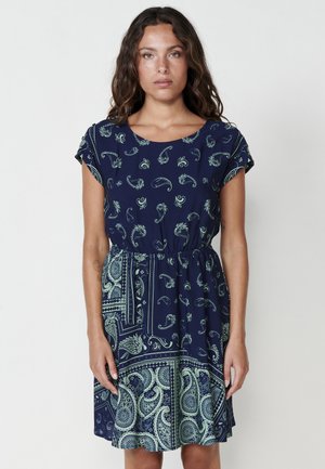 Marineblaues Kleid mit kurzen Ärmeln, das ein grünes Paisleymuster aufweist und eine elastische Taille für einen gerafften Effekt hat.