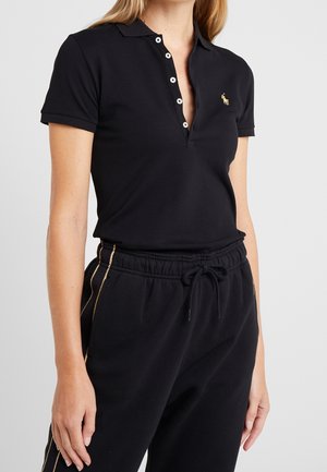 Zwart poloshirt met korte mouwen, een knoopsluiting aan de kraag en een klein gouden embleem. Gecombineerd met zwarte sweatpants met gouden zijstrepen.