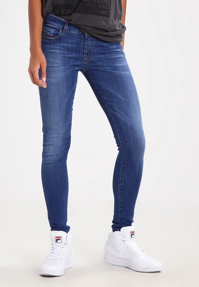 Modré džíny skinny z denimu s hladkou texturou, pěticiklovým designem a kontrastním šitím; spárované s bílými vysokými teniskami.