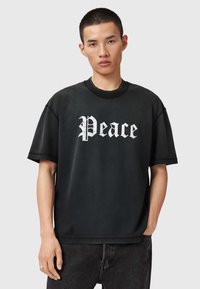 Fekete pamut rövid ujjú póló, kerek nyakkivágással, fehér "Peace" felirattal vastag betűtípussal. Egyszerű dizájn enyhe kopottsággal.