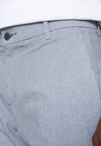 Light gray textured trousers with a small white dot pattern, featuring a button closure and standard pockets. No visible branding.