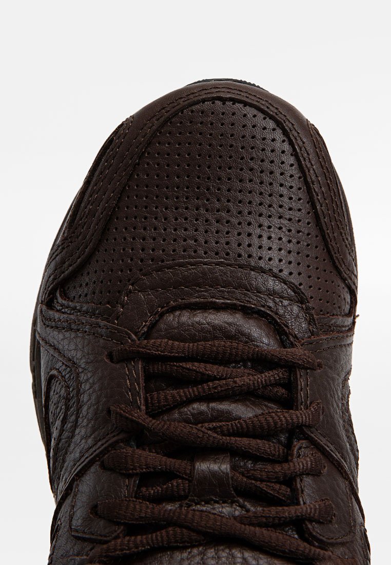 Sneaker in pelle marrone scuro con area della punta perforata e lacci marroni coordinati, vista dall'alto che mostra i dettagli della texture.