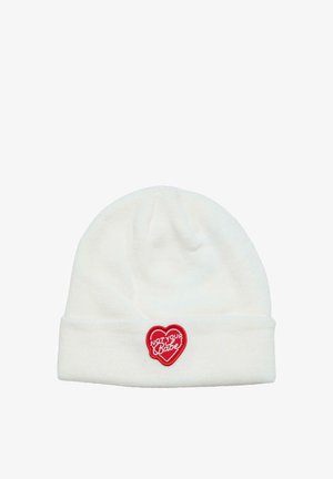 White knitted beanie with a cuff, featuring a red heart-shaped patch that reads "NOT YOUR BABE" in white text. Soft texture.