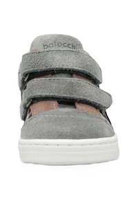 Sneaker in suede grigio con due cinturini in Velcro regolabili, dettagli marroni a contrasto, punta rotonda e suola in gomma bianca.