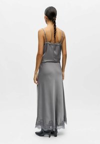 Robe longue en satin gris avec bretelles ajustables, ornée d'accents en dentelle à l'ourlet. Le dos est lisse avec une taille cintrée et une jupe fluide.