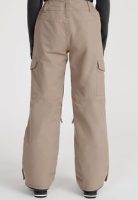 Beige cargo pants with a relaxed fit, featuring side pockets, a high waistband, and zippers at the ankles for adjustable openings.