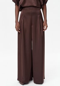 Bruine wijde broekspijpen van gladde stof, met plooien aan de voorkant en een hoge tailleband voor een op maat gemaakte uitstraling.