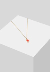 Gul kæde med en rød flamingo vedhæng. Vedhænget har en detaljeret lys farvekant og en enkelt ben strakt ud.
