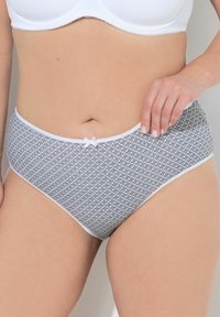 Vita högmidjade underkläder med ett svart geometriskt mönster, med en vit kant och en liten rosett detalj vid midjan. Mjuk tygtextur.