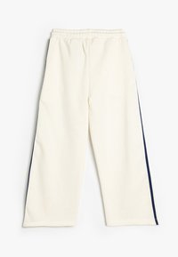 Pantalones de chándal color crema con un corte relajado, que presentan rayas laterales en un azul marino oscuro y una cinturilla elástica para mayor comodidad. Material suave de mezcla de algodón.