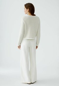 Striped sweater in cream and beige, cropped design, paired with wide-legged white pants. Textured knit and simple silhouette.