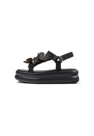 Sandalia de plataforma negra con suela gruesa, correas ajustables y detalles decorativos de mariposas en la correa superior.