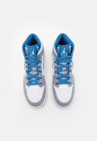 Baskets montantes blanches et grises avec des lacets bleus, présentant une boîte à orteils perforée, un col rembourré à la cheville et un logo emblématique sur la languette.