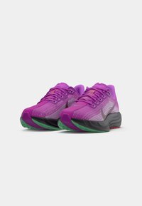 Des chaussures de sport purple avec un dessus en maille texturée, un embout arrondi et une semelle rembourrée ornée d'accents verts et rouges.