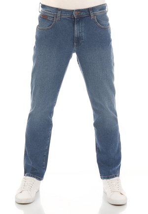 Blauwe denim jeans met een rechte pijp, vijf zakken, een merkembleem op de tailleband en een klassieke indigowas finish. Gecombineerd met witte sneakers.