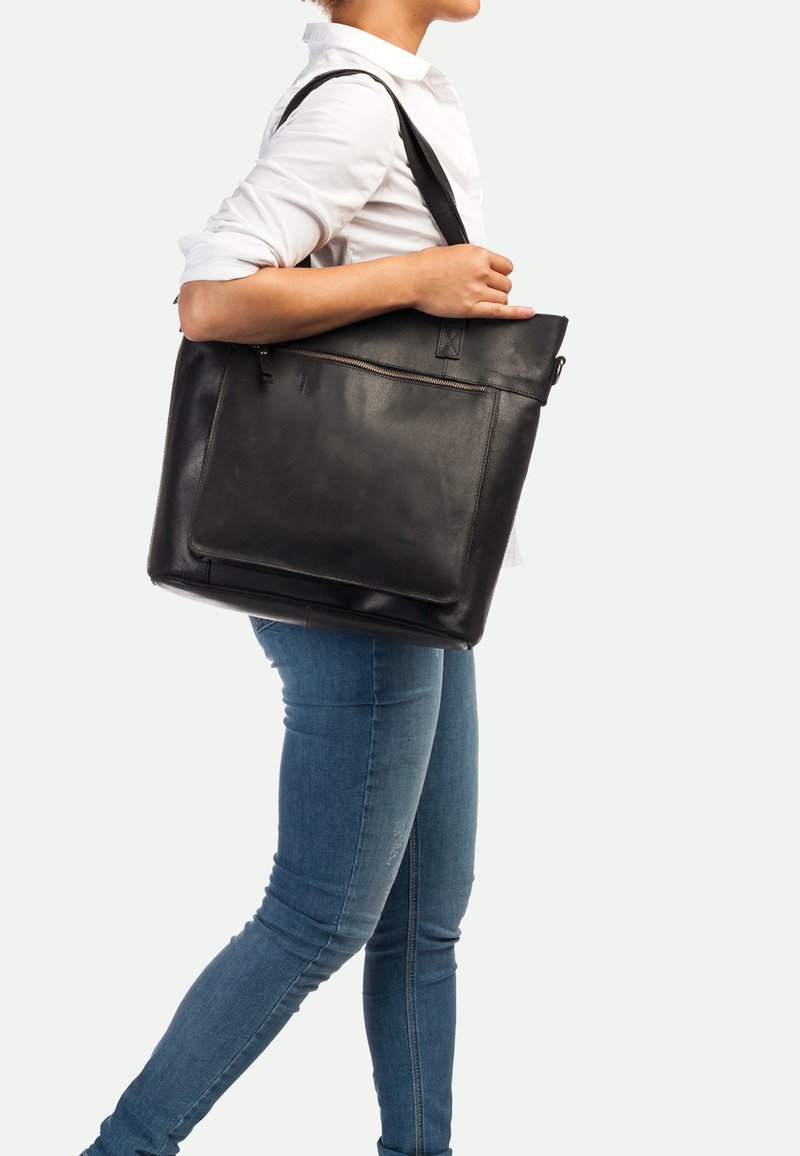 Zwarte leren tote bag met een bovenste ritssluiting, een buitenzak aan de voorkant en een verstelbare schouderriem, met een gladde textuur.