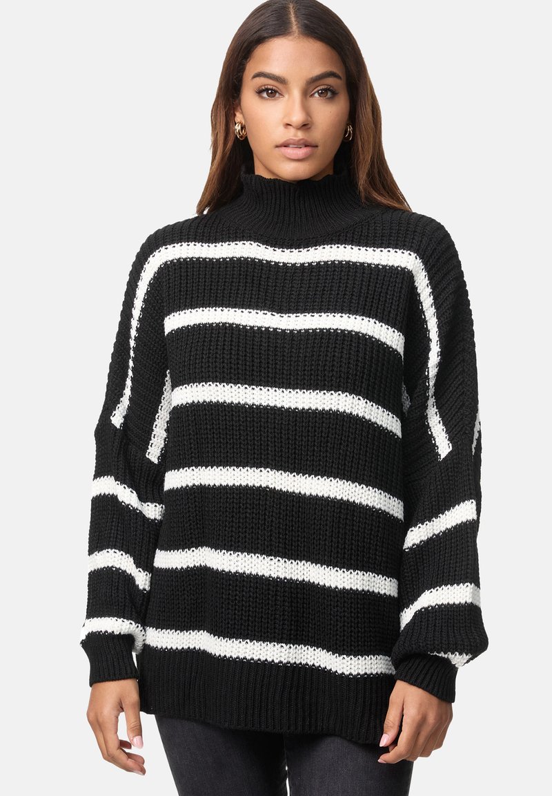 Maglione lavorato a maglia a righe bianche e nere con colletto alto, vestibilità ampia e polsini a coste. Presenta una trama spessa e maniche larghe.