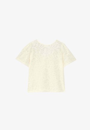 Haut à manches courtes en tissu crème doux, avec un motif floral subtil. Col rond, coupe décontractée et texture lisse.