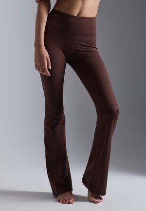 Brown flared leggings made from stretch fabric, featuring a high waistband and smooth texture, designed for comfort and flexibility.