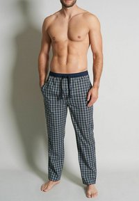 Pantalons de pyjama à carreaux bleu marine et blanc avec une taille élastique et un cordon de serrage. Fabriqués en tissu léger, avec des poches latérales et une coupe décontractée.