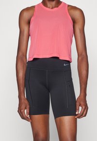 Różowy siatkowy tank top sportowy z okrągłym dekoltem, w zestawieniu z czarnymi dopasowanymi szortami z bocznymi kieszeniami i kontrastowym przeszyciem.
