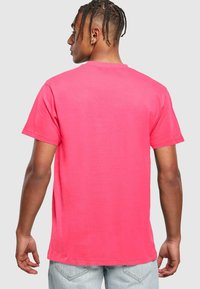 T-shirt in cotone rosa con maniche corte, di colore uniforme, vestibilità comoda e scollo rotondo classico. Presenta un design minimalista senza grafiche.