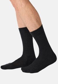Sorte crew-sokker med ribbet kant, lavet af blødt materiale, med en glat tekstur og tætsiddende pasform, der rækker til midt på læggen.