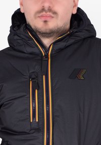 Czarna puchowa kurtka z kapturem, z wielokolorowymi detalami na suwaku i logo na piersi. Gładka tekstura, lekka konstrukcja.