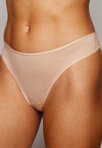 Nude farby, polpriesvitné bikiny s nízkym pásom a minimálnym pokrytím, s hladkými okrajmi a jemnou textúrou.