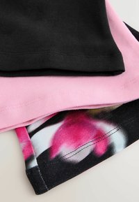 Kolme kangaspalaa pinottuna: mustaa puuvillaa, pehmeää vaaleanpunaista puuvillaa ja kukkakuosinen kangas, jossa on vaaleanpunaisia ja valkoisia kukkia mustalla taustalla.