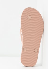Light pink flip-flop sole with a wavy texture. Features two circular size indicators: "S" and "L." Made of flexible rubber material.