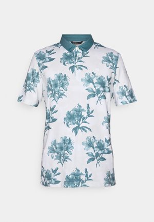 Kortermet polo skjorte laget av hvitt stoff med et teal blomsterdesign. Har en teal krage og tre-knapps knappestolpe.