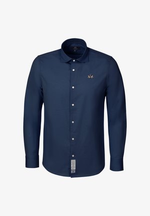 Marineblaues langärmliges Hemd mit Knöpfen und Kragen, weißen Knöpfen, gesticktem Logo auf der Brust und einem Pflegeetikett nahe dem unteren Saum.