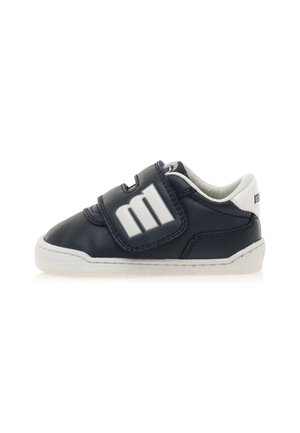 Zapatilla de cuero azul marino con suela de goma blanca, correa de Velcro y un llamativo detalle del logo en la correa. Diseño de puntera redondeada con cuello acolchado.