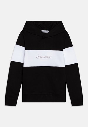 Sweat à capuche noir avec une bande horizontale blanche sur la poitrine et les manches, avec le logo "Calvin Klein Jeans" centré sur la bande.