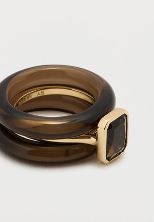 Inel maro din rășină, cu două benzi interconectate, decorat cu o montură dreptunghiulară în ton auriu și o piatră prețioasă fațetată, de culoare închisă.