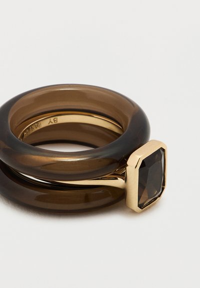 Inel maro din rășină, cu două benzi interconectate, decorat cu o montură dreptunghiulară în ton auriu și o piatră prețioasă fațetată, de culoare închisă.