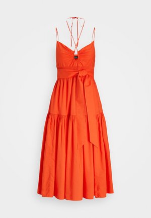 Oranje katoenen jurk met een getailleerde buste, spaghettibandjes en een strikmiddel. Heeft een uitlopende, gelaagde rok en een geplooide halslijn.