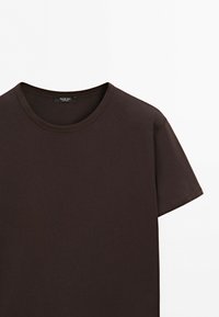 T-shirt marron foncé à manches courtes avec col rond, coutures visibles et étiquette de marque à l'intérieur du col sur fond blanc.