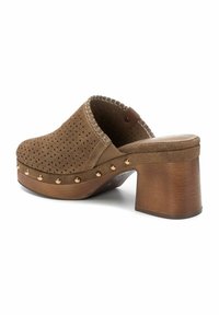 Bruine suede klomp met geperforeerd ontwerp, dikke houten blokhak, gouden studaccenten en gestikte randafwerking.