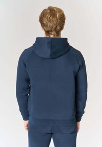 Felpa blu navy con cappuccio, caratterizzata da una texture liscia, polsini e orlo a costine, progettata con una vestibilità rilassata e maniche raglan.