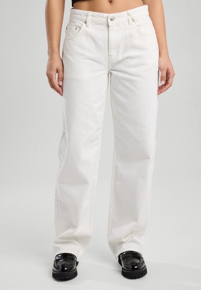 White denim pants with a loose fit, featuring a button closure, belt loops, and front pockets. The fabric has a smooth texture.