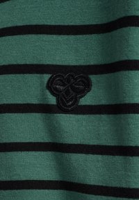 Grön och svart randig tröja med mjuk textur; har en broderad logotyp centrerad på tyget.