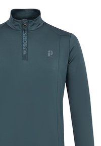 Tirkizni pulover s četvrtastim zipom, izrađen od glatkog materijala, s povišenim ovratnikom i logom na prsima. Ergonomski šavovi poboljšavaju uklapanje i pokretljivost.
