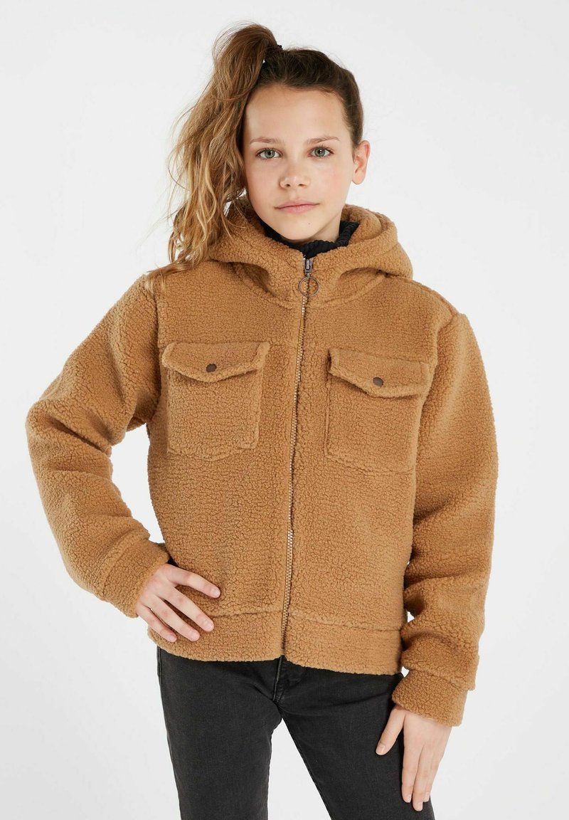 Giacca in pile marrone con zip frontale, cappuccio e due tasche sul petto. Presenta una superficie morbida e testurizzata e un design cropped. Maglietta nera visibile.