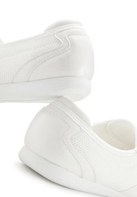 White athletic shoes made of mesh and leather, featuring a smooth heel, textured pattern on sides, flexible sole, and rounded toe design.