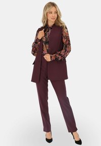 Burgundowy dopasowany kamizelka i spodnie z wzorzystą bluzką z długim rękawem. Posiada pojedyncze zapięcie na guzik i dopasowany krój. Czarny obcas uzupełnia całość.