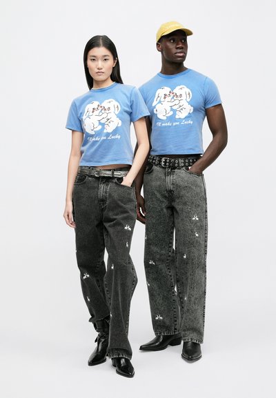 Blå croppade t-shirts med tecknade motiv, kombinerade med svarta jeans i denim med vit kaninbroderi, bärs med svarta ankelboots.